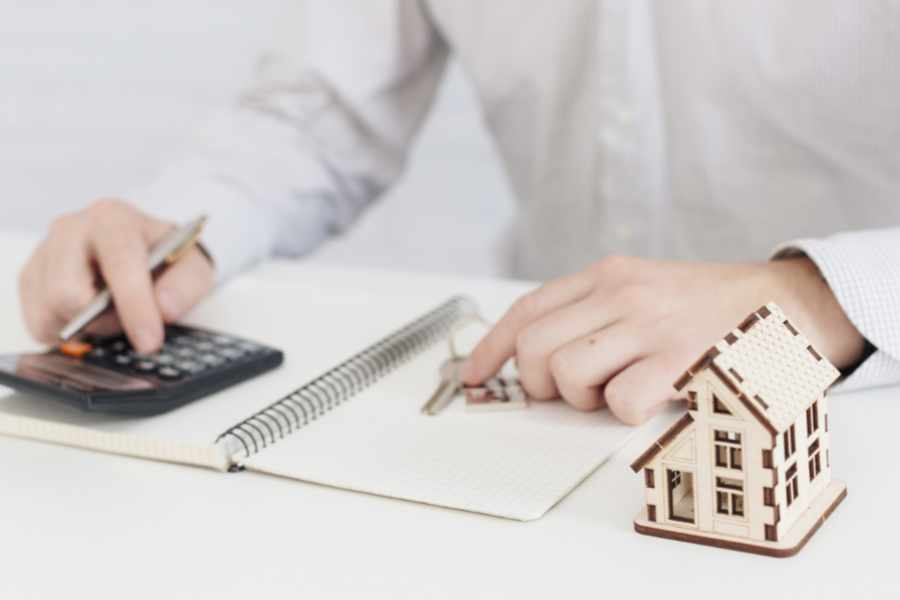 Hausverkauf vorbereiten – Immobilienmakler kalkuliert Immobilienwert mit Taschenrechner