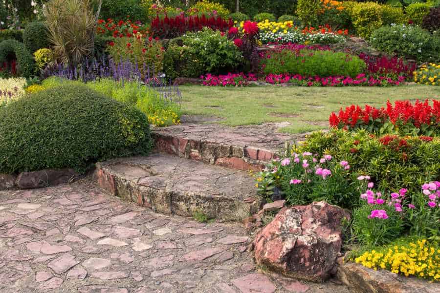 Gepflegte Gartenanlage mit Natursteinweg und blühenden Beeten
