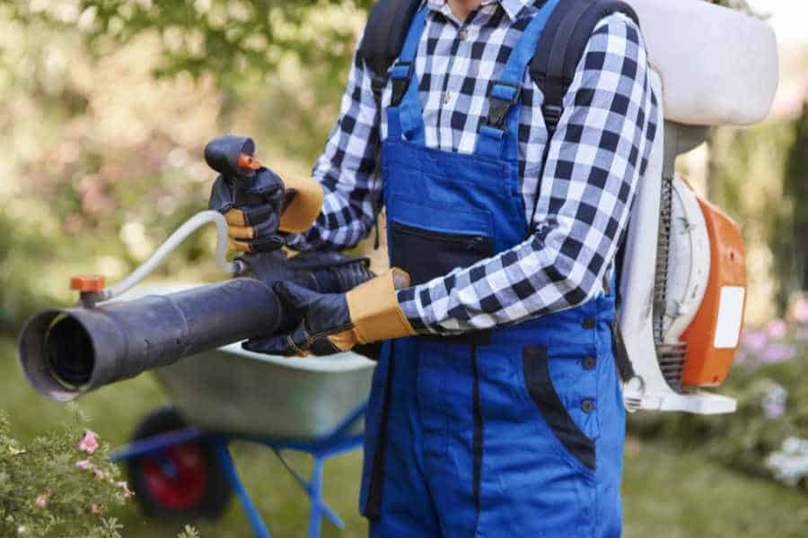 Gartenarbeiter mit Laubbläser bei professioneller Grundstücksreinigung