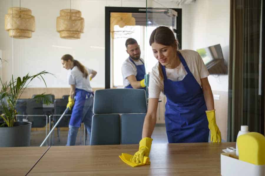 Reinigungskraft wischt Tisch in leerer Wohnung